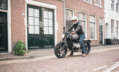 Man riding bicycle on street against building in city