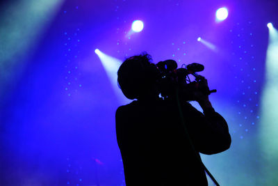 Rear view of man photographing at music concert