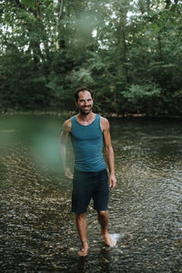 Full length of man standing on lake in forest