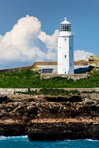 Lighthouse by sea against sky