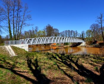 Arch bridge over river against clear blue sky
