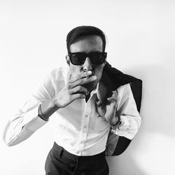Young man smoking against white background