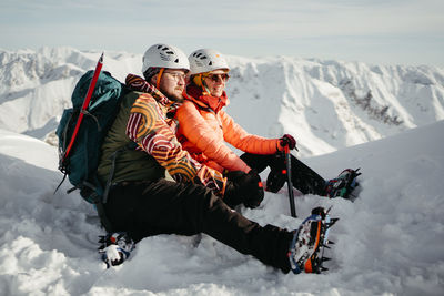 Low angle view of woman sitting on snowcapped mountain