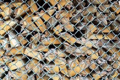 Stack of firewood logs for winter through blue grid. rustic lumber wooden background.