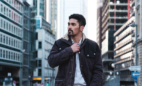 Young man standing against buildings in city