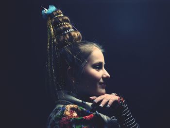 Close-up of girl looking away against black background