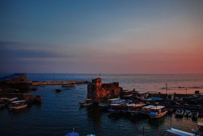 Boats moored on sea against sky during sunset