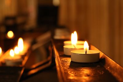 Close-up of burning tea light candles on shelf
