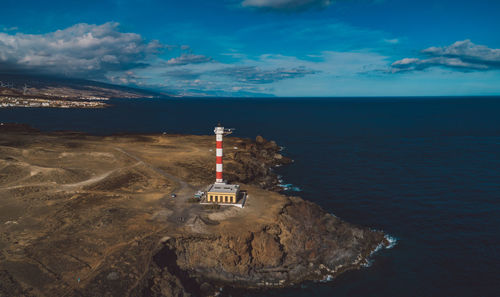 Lighthouse by sea against sky