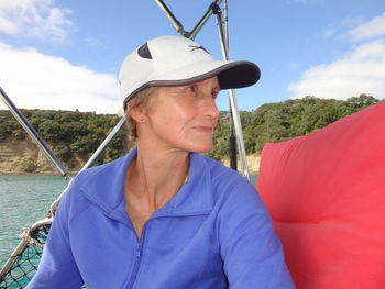 Mature woman sitting in boat on lake against sky