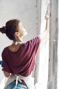 Side view of woman standing against wall