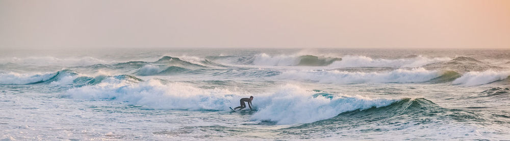 Person surfing in sea against sky