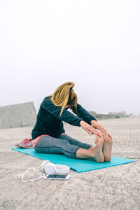 Woman doing yoga against clear sky