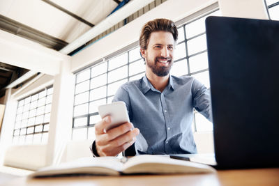 Young man using mobile phone while sitting on table