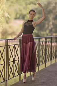 Portrait of young woman standing against railing