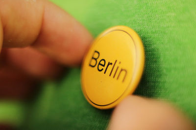 Close-up of hand holding yellow badge with text