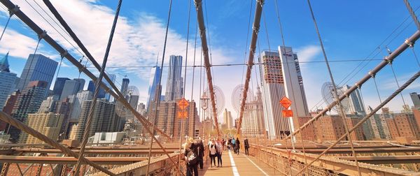 People walking on bridge against buildings