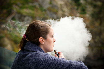 Portrait of young woman smoking outdoors