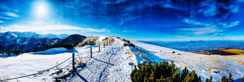 Panoramic view of snowcapped mountains against blue sky