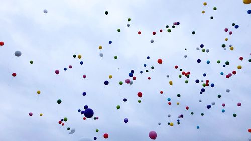 Low angle view of multi colored balloons against sky