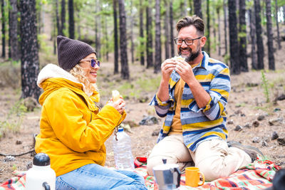 Couple eating food while sitting in forest