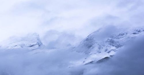 Snow covered mountains against cloudy sky