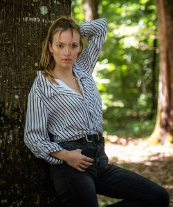 Young woman standing against trees