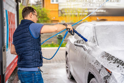 Rear view of man cleaning car