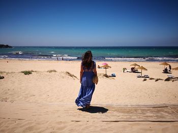 Full length of woman walking on sand at beach against sky