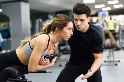 Trainer assisting woman exercising in gym