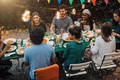 High angle view of multi-ethnic young friends enjoying dinner at table during garden party
