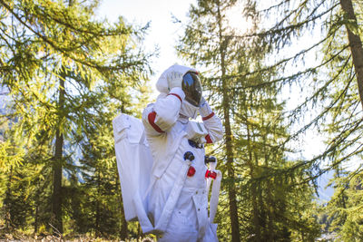 Astronaut looking away while standing in forest