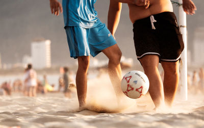 People playing soccer ball on beach