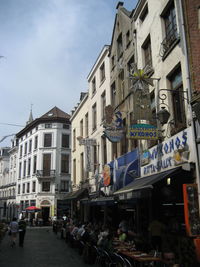 People on street amidst buildings in city against sky