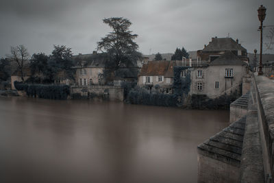 Town by river against sky