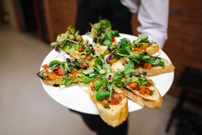 Catering food at the party. catering service. the waiter holds a plate with bruschetta.