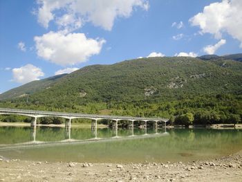 Scenic view of river by mountains against sky