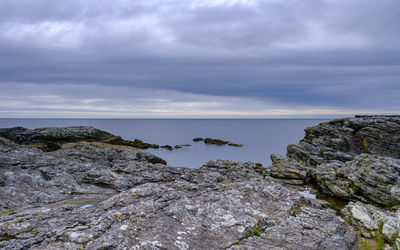 Rocks on sea shore against sky