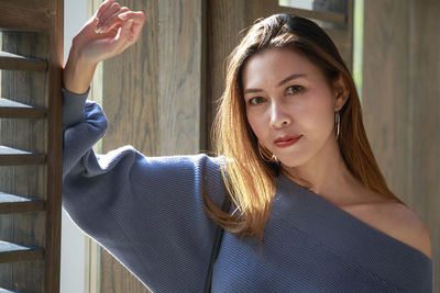 Close-up portrait of mid adult woman standing by window at home