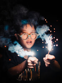 Portrait of happy woman with fire crackers at night