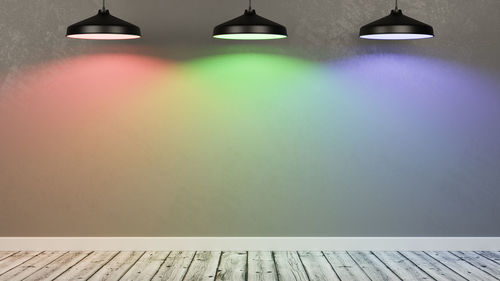 Low angle view of illuminated lights on table against wall