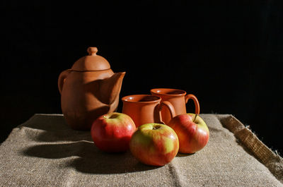 Close-up of apples in bowl on table against black background