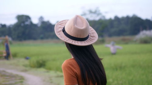 Rear view of woman wearing hat standing on field