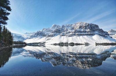 Frozen lake by snowcapped mountains against sky