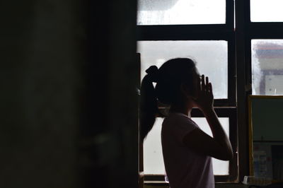 Side view of woman at home by window