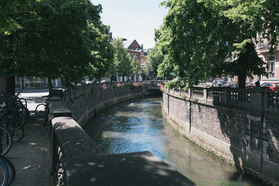 Footbridge over canal in city against sky
