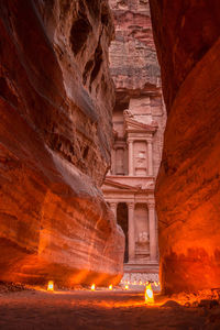 Illuminated lamps amidst rock formations leading towards al khazneh