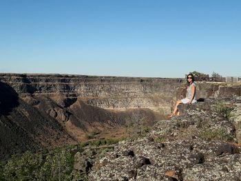 Woman standing on rock against clear sky