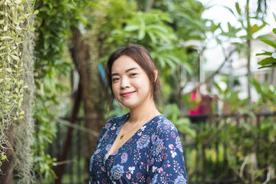 Portrait of young woman standing against plants