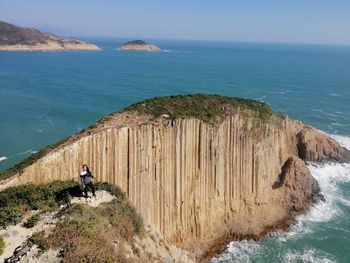 Woman on rocks by sea against sky